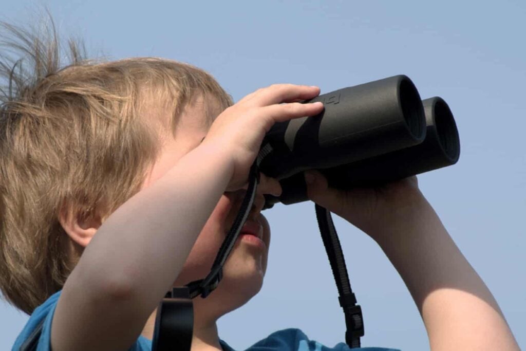 child with binoculars looking out
