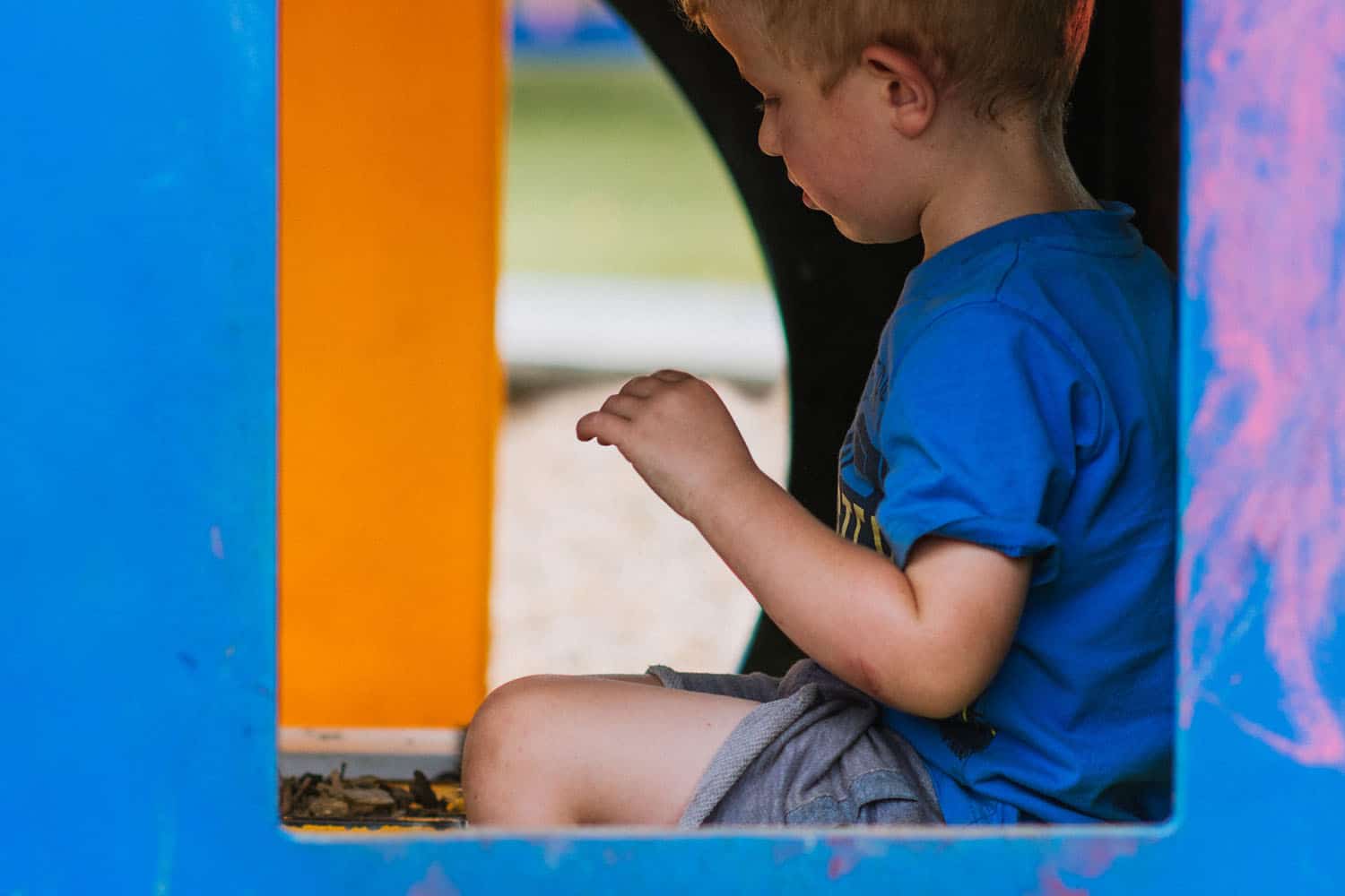 Child sitting alone in enclosed space in preschool playground