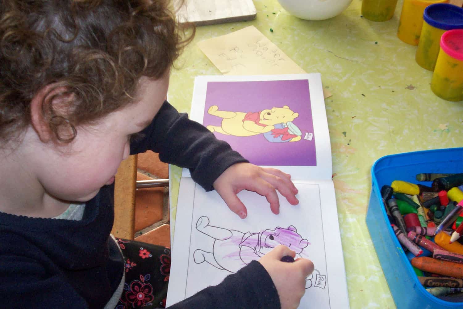 child is drawing in colouring-in book