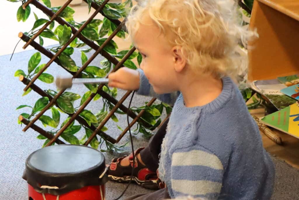 Bang, bang, bang - toddler beats drum at early childhood centre.