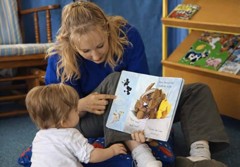 early childhood education qualified teacher reading a book with a child. Illustrating the importance of ECE teacher qualifications.