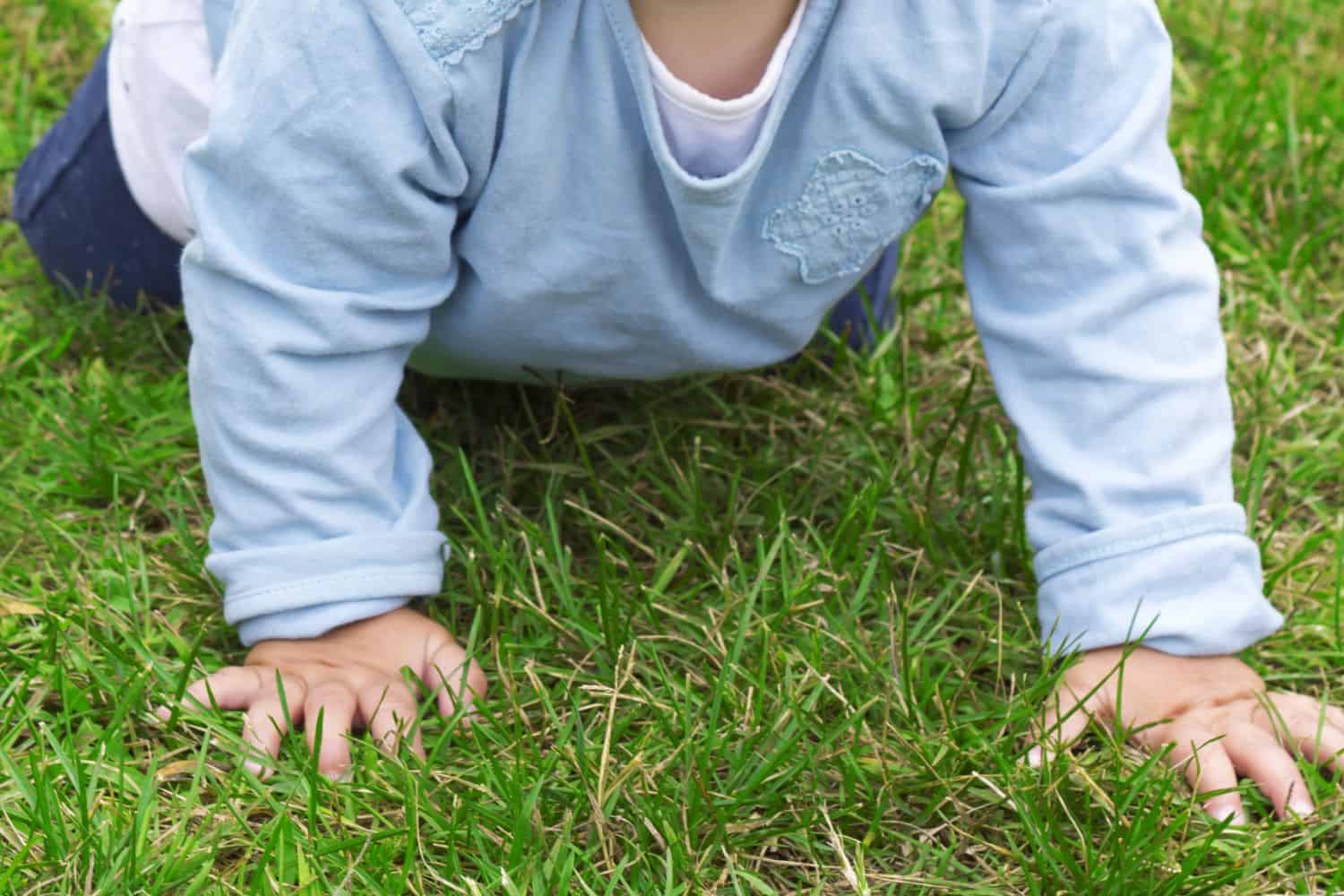 toddler enjoys softness of grass for physical movement at early childhood centre NZ.