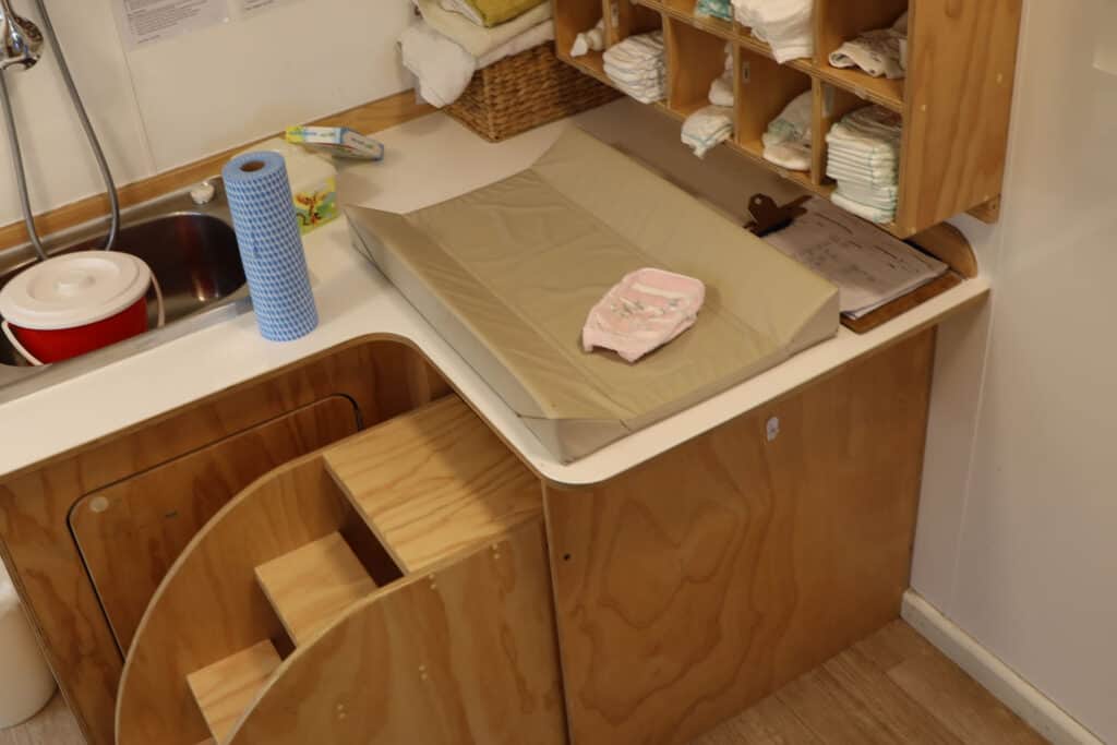 Men changing nappies. Nappy change table for infants at early childhood centre