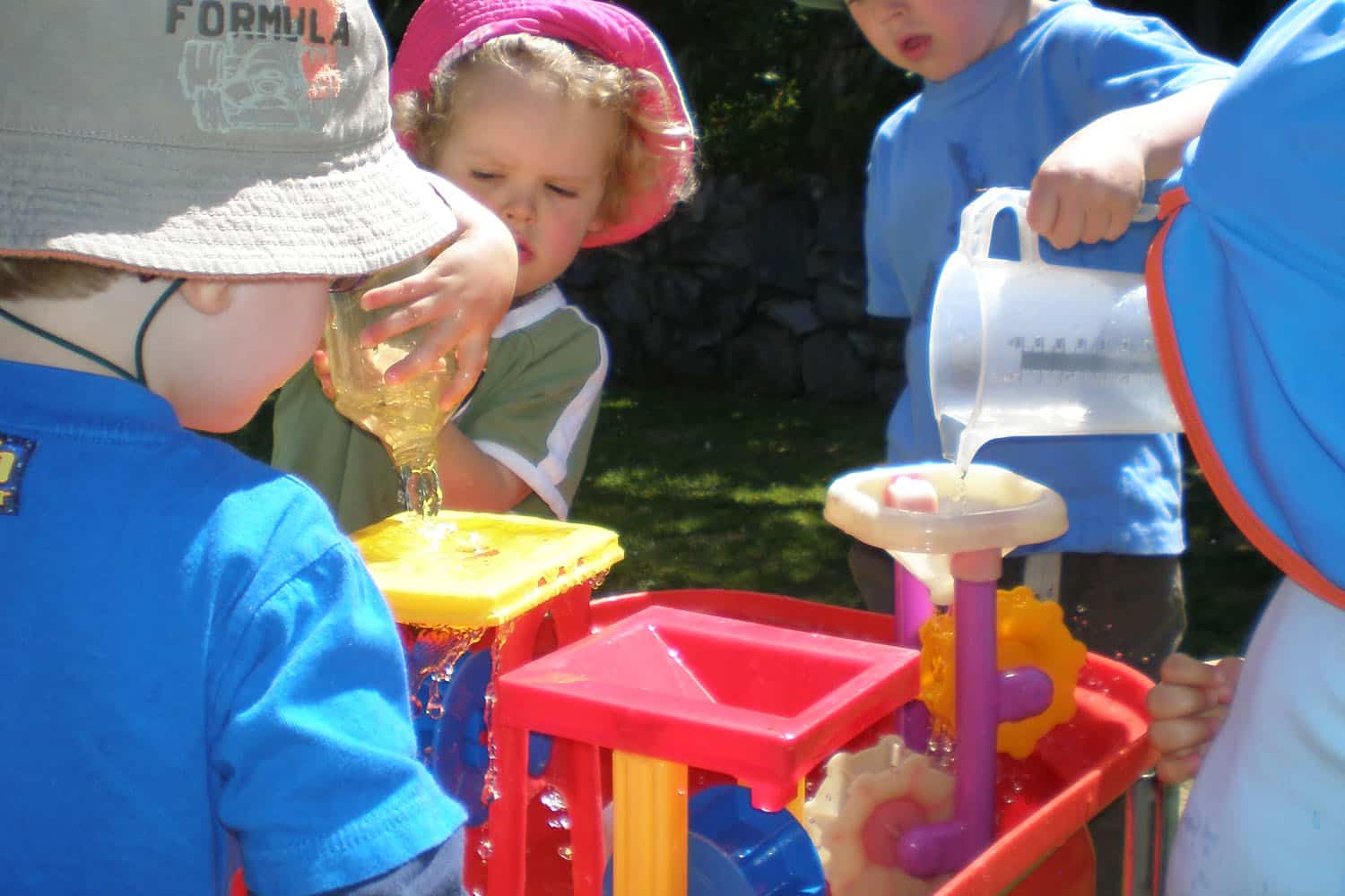 sun protection and children with sunhats engaged in waterplay in home-based ECE